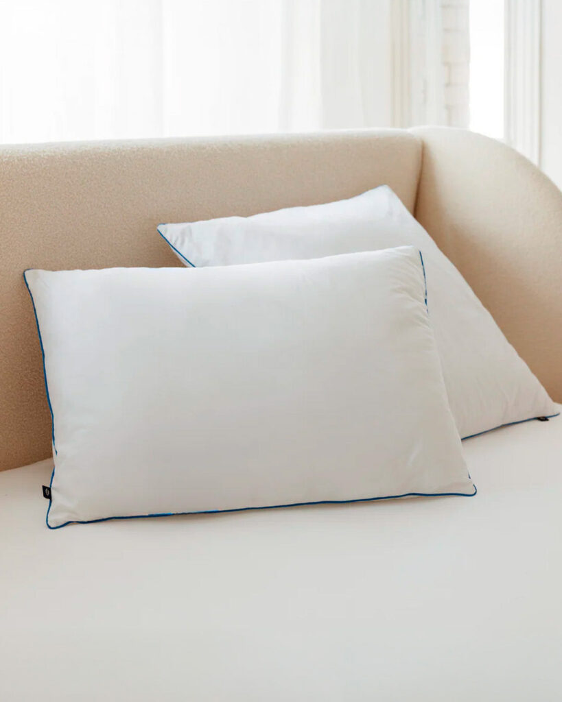 Oreillers Morphea Fluffy posés sur un lit tapissé beige