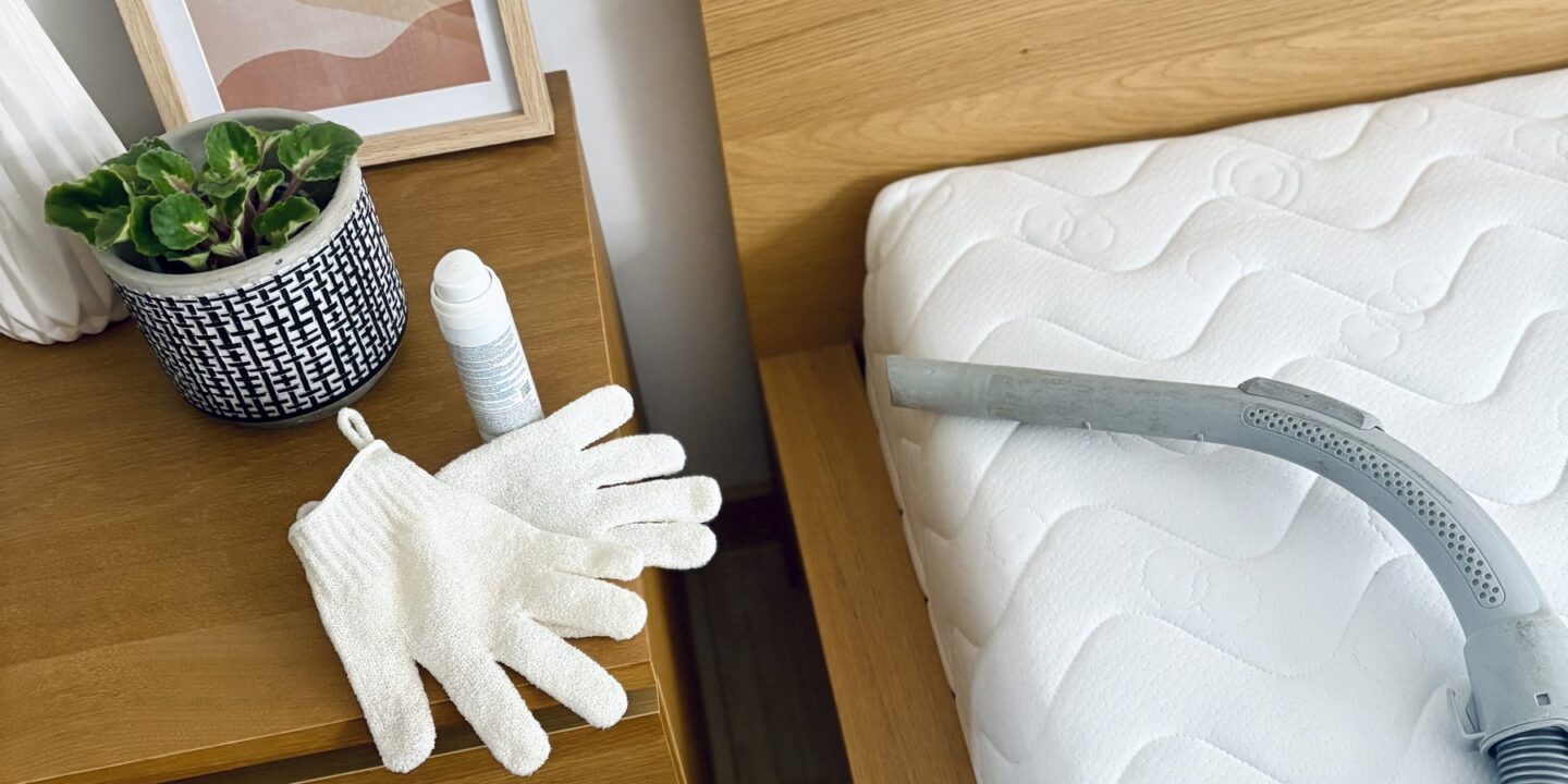 Aspirateur, gants et spray de nettoyage posés près d'un matelas