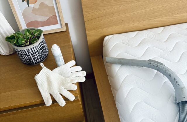 Aspirateur, gants et spray de nettoyage posés près d'un matelas