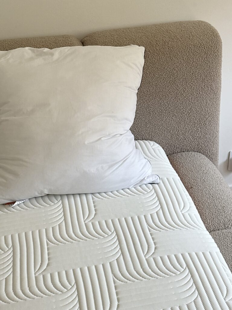Un oreiller Emma Original Confort seul, posé contre la tête de lit sur le matelas