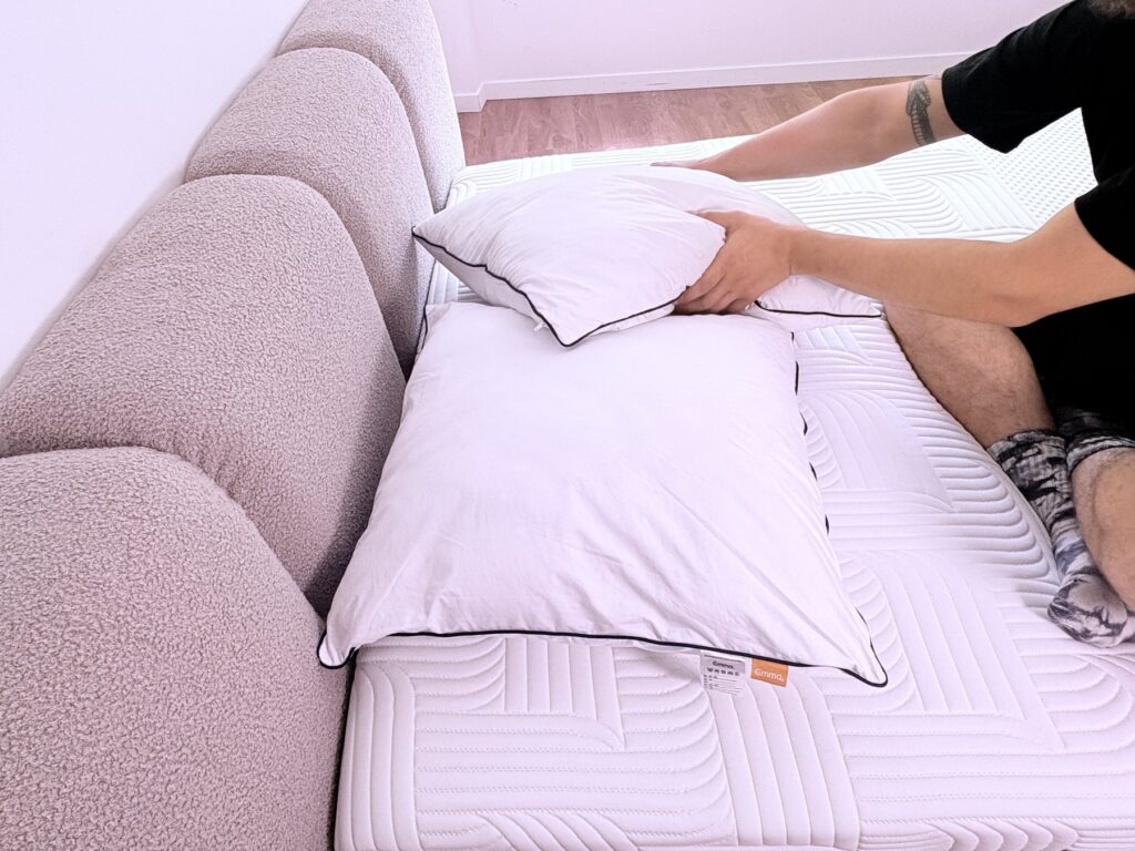 Testeur tapotant les côtés de l'oreiller Emma Original Confort pour lui redonner du volume