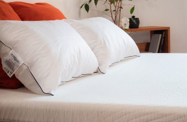 Oreillers blancs et coussins rouges posés sur un matelas