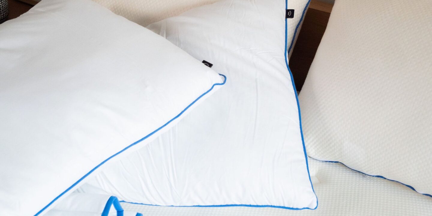 Oreillers blancs passepoilés de bleu et couette sur un lit