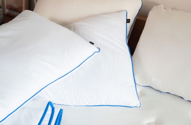Oreillers blancs passepoilés de bleu et couette sur un lit