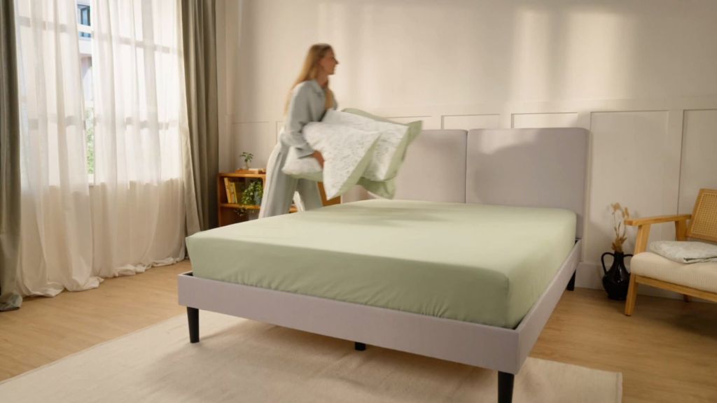 Femme faisant son lit avec la parure Emma en percale verte
