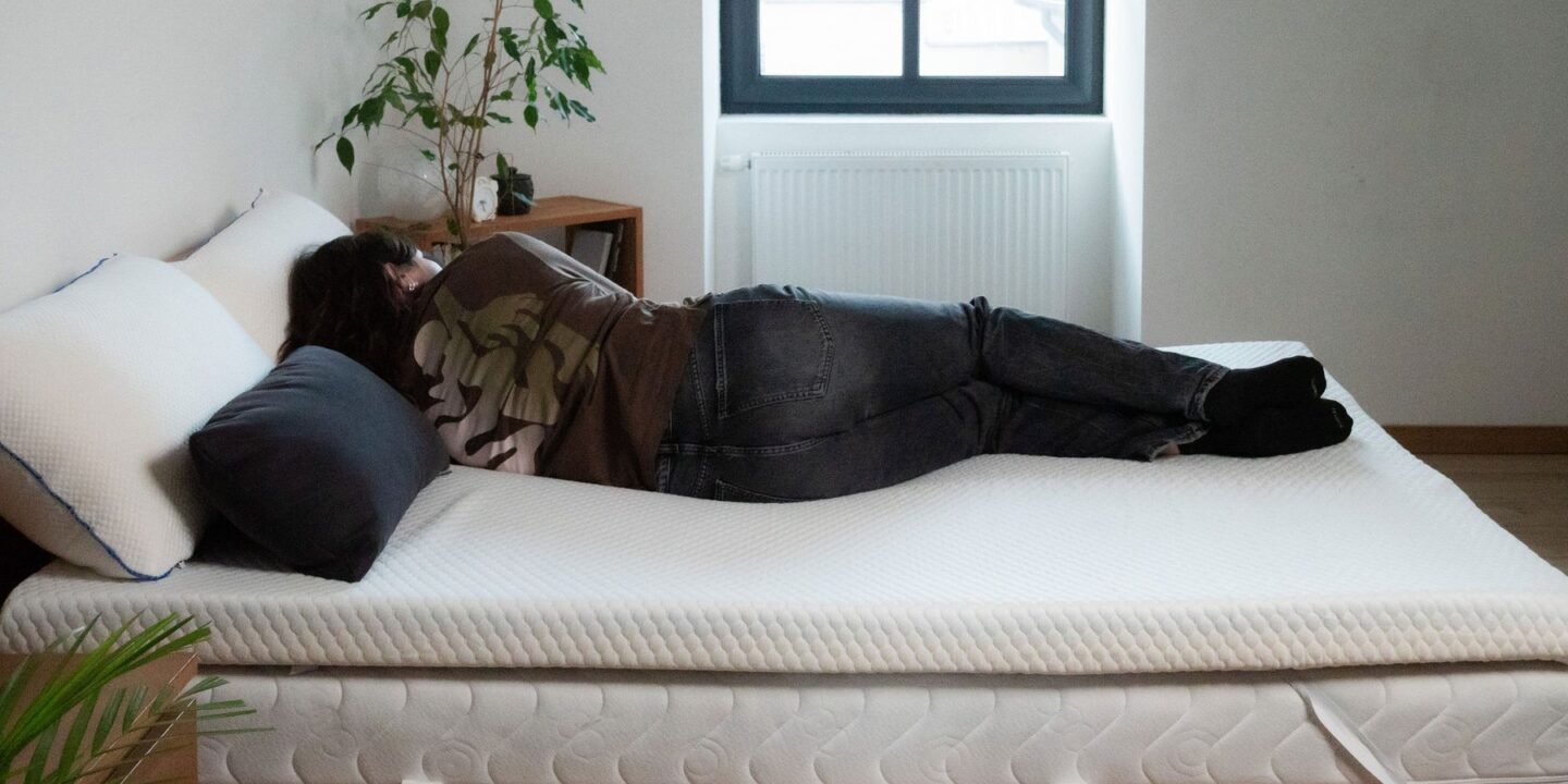 Personne allongée sur le côté sur un surmatelas, chambre lumineuse