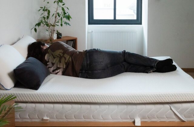 Personne allongée sur le côté sur un surmatelas, chambre lumineuse