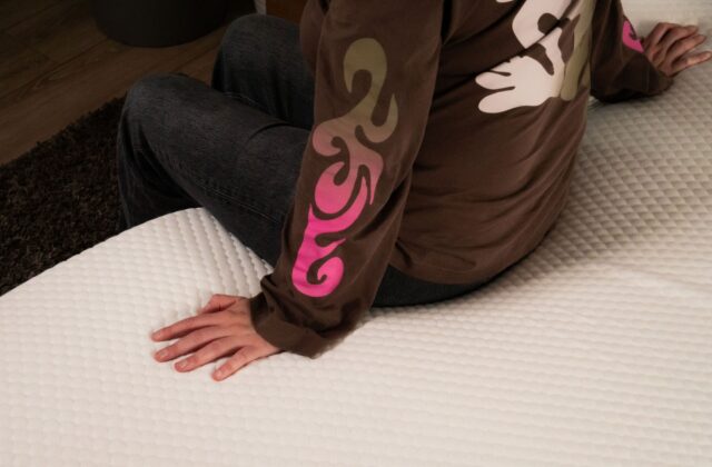 Personne assise au bord du lit, la main posée sur le surmatelas