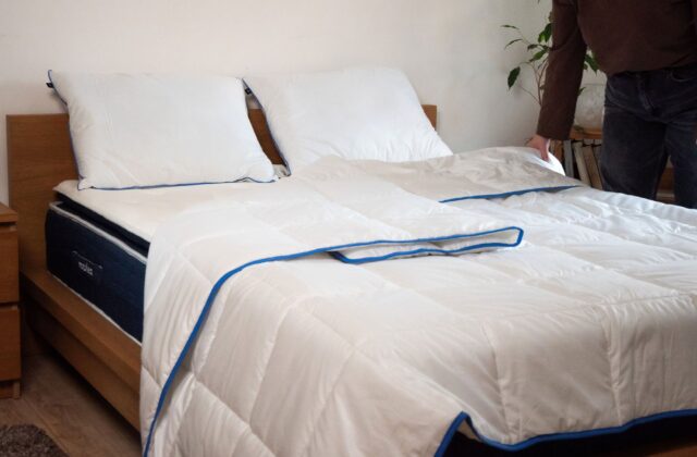Personne étalant une couette blanche sur un lit avec oreillers