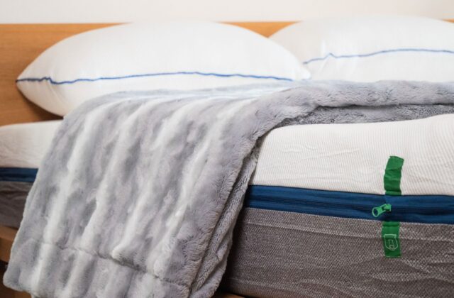 Plaid gris en fausse fourrure et oreillers sur un matelas