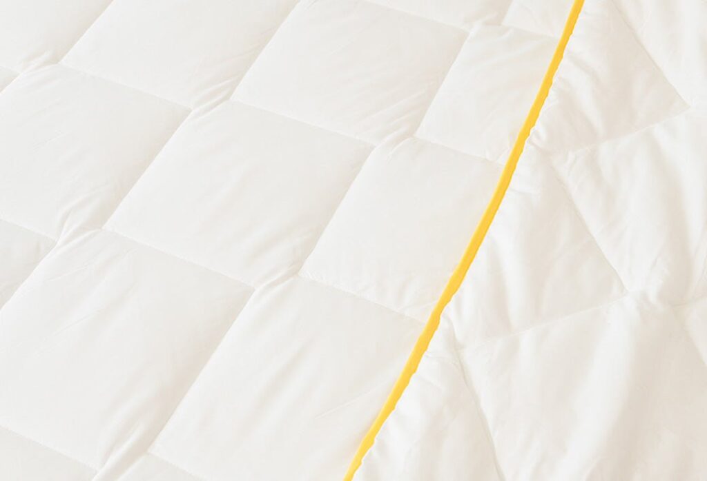 Slome Couette légère, gros plan du piquage en losanges et du biais jaune