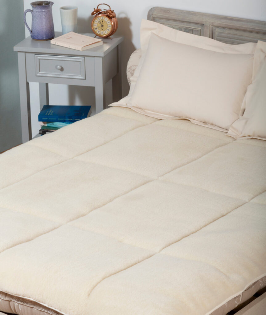 Surmatelas Ardelaine Confort en laine piqué en carrés, vu de trois quarts sur un lit