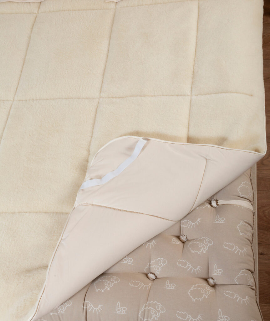 Coin replié du surmatelas Ardelaine Confort montrant la face velours de laine et la face en coton