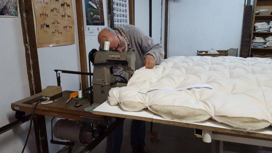 Artisan cousant les côtés d’un surmatelas en laine dans l’atelier Dormilaine du Tarn