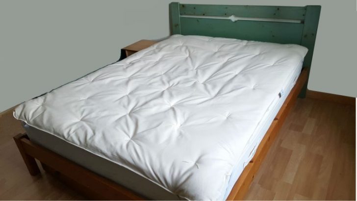 Surmatelas Dormilaine en laine capitonné installé sur un matelas dans une chambre
