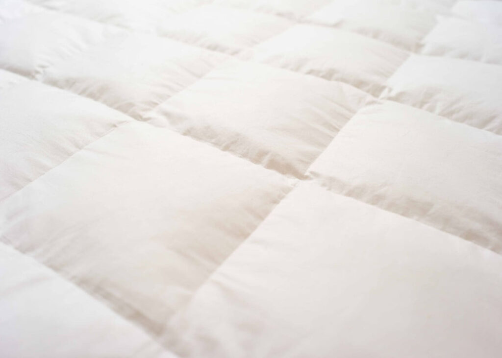 Piqûres en carreaux du surmatelas Kipli en plumes et duvet, vue rapprochée