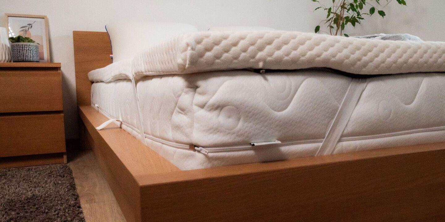 Vue latérale d'un surmatelas posé sur un lit en bois