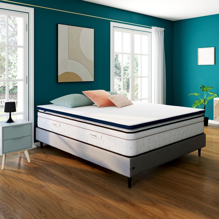 Surmatelas Nuit Faubourg Odéon sur un lit, chambre aux murs bleu canard