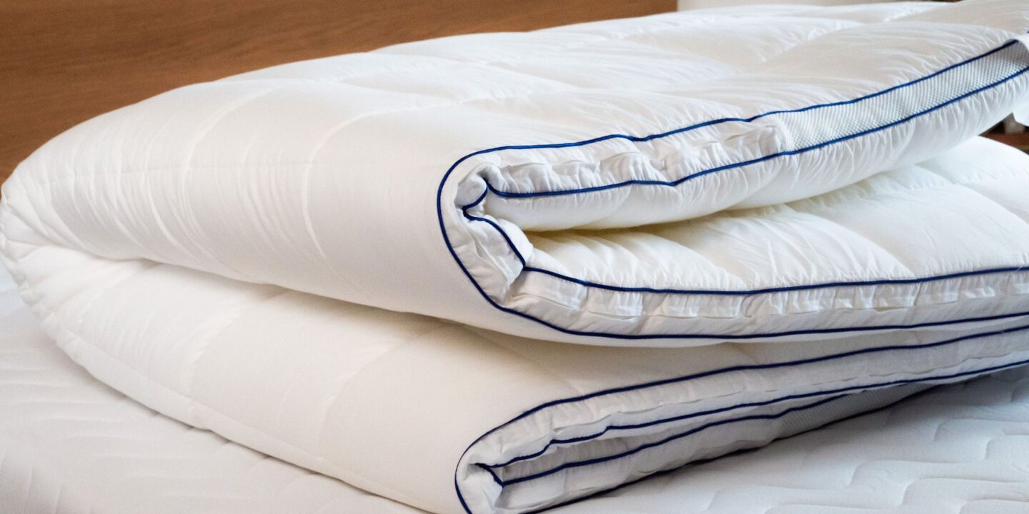 Surmatelas plié en trois posé sur un lit