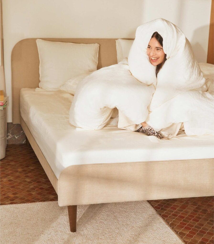 Femme sous la Couette légère Plus Tediber assise sur un lit