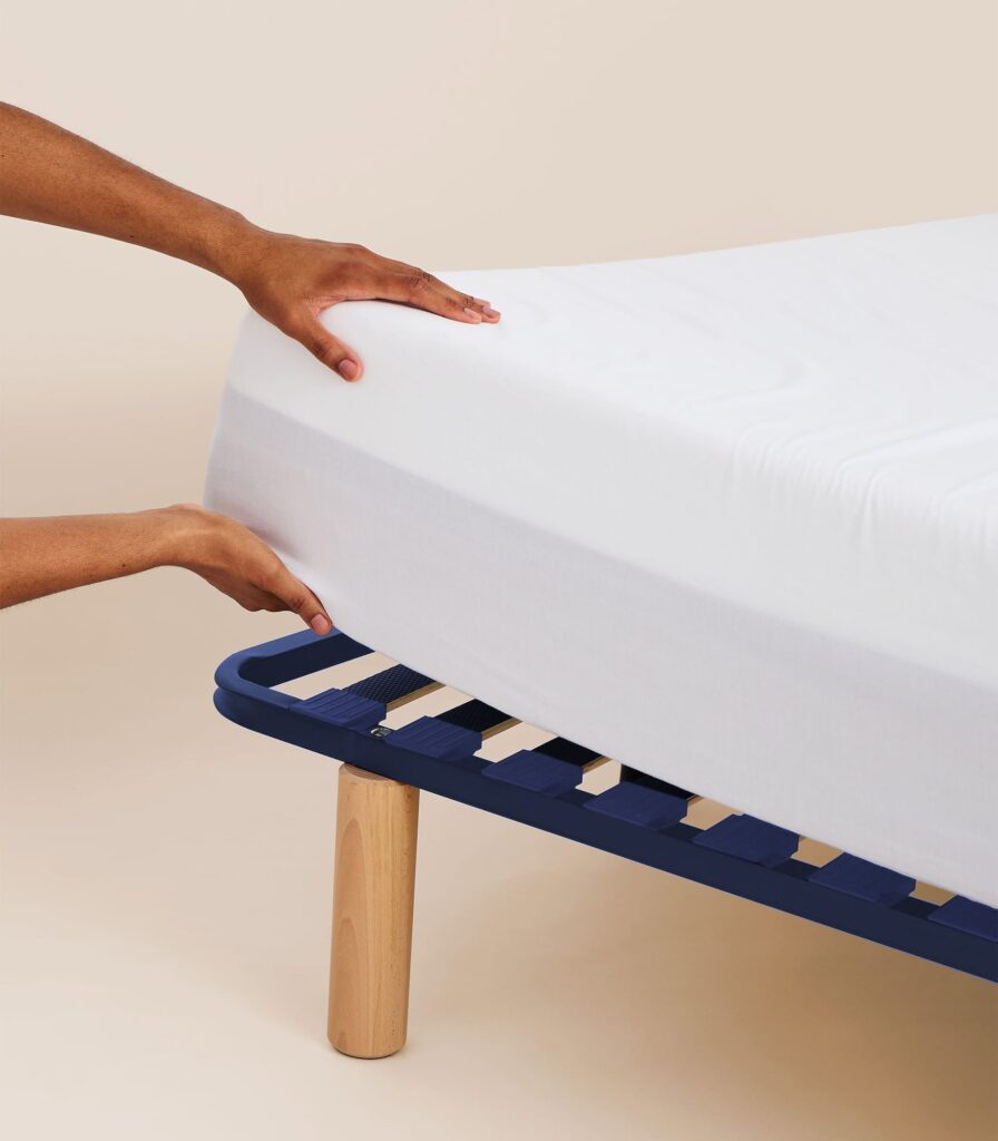 Tediber Sommier à lattes avec un matelas, mains posant le drap housse