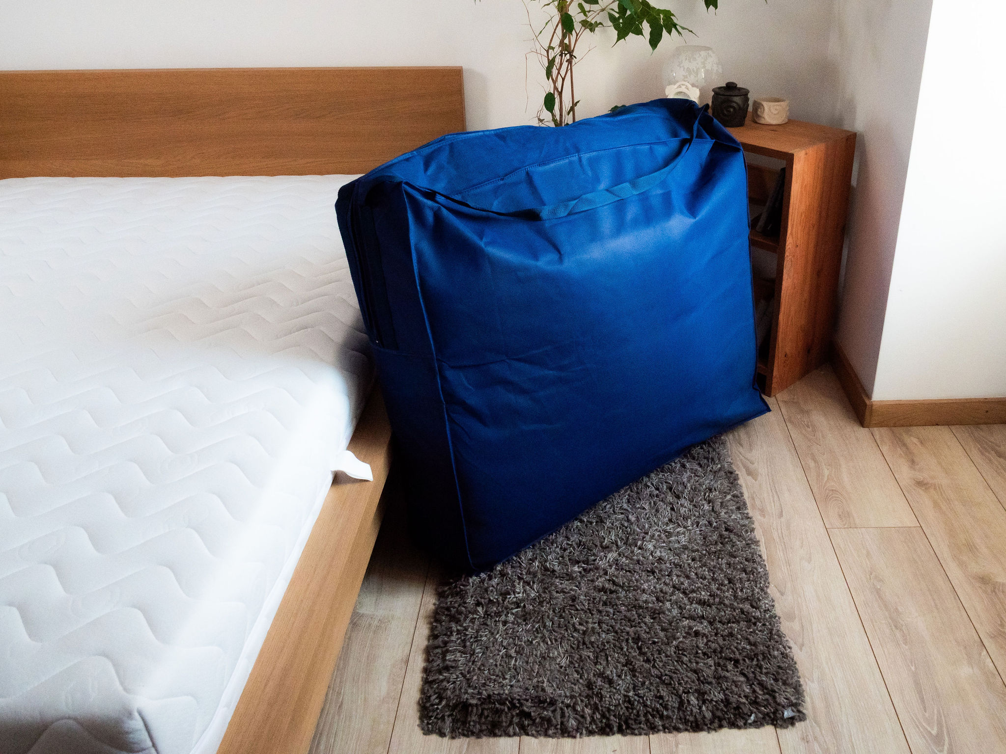 Sac de rangement bleu du Bdreams Soft posé au pied du lit