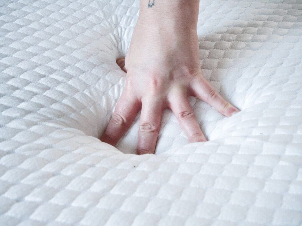 Main qui s'enfonce dans la housse matelassée du Nyte Air