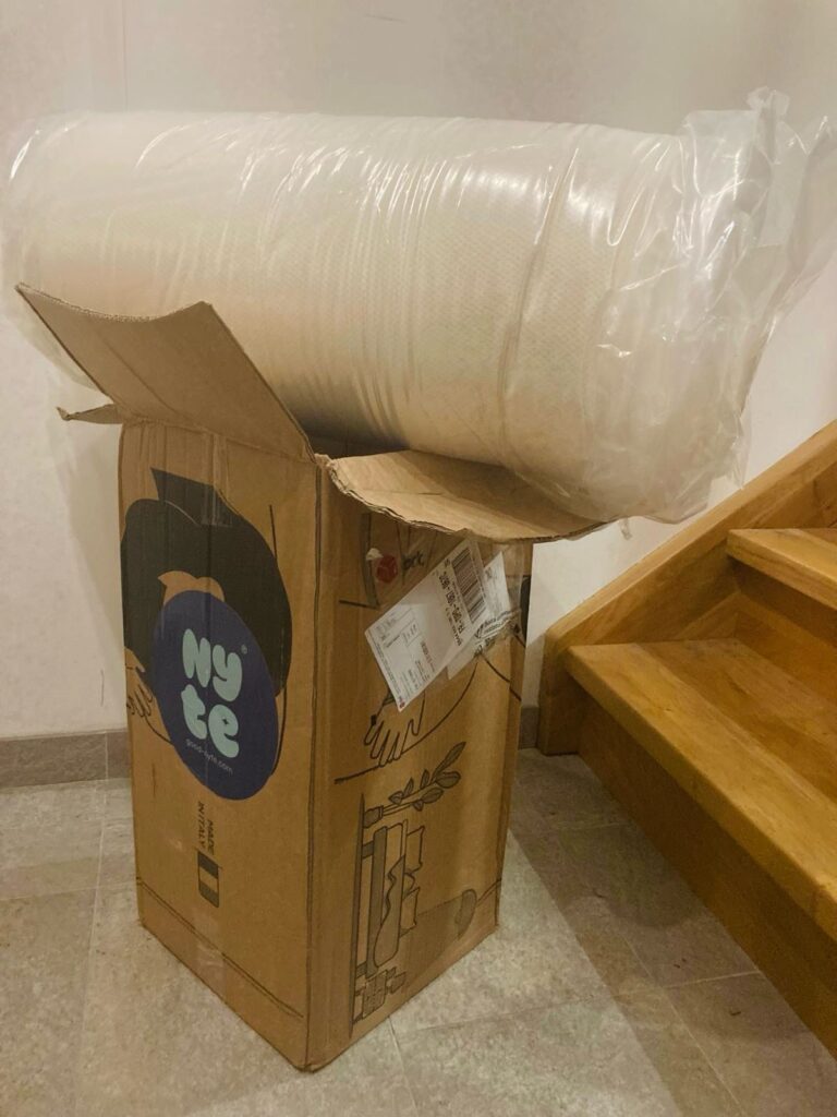 Surmatelas Nyte Cosy roulé sortant de son carton